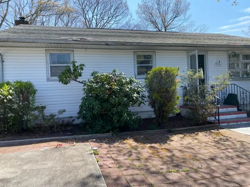 White ranch with tall shrubs along the front, Mastic, NY